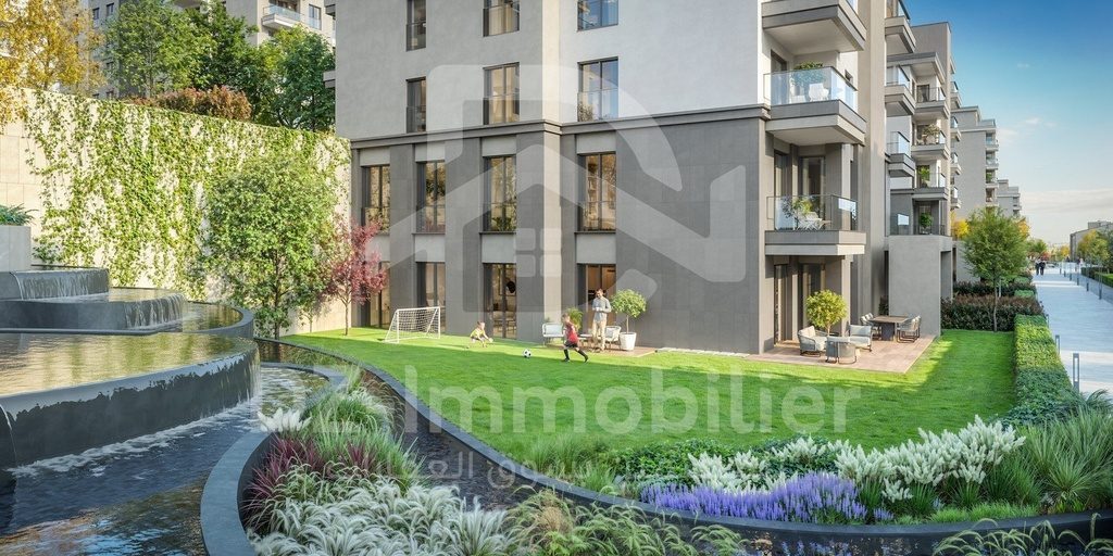 Rendu 3D : pelouse et plan d’eau devant un immeuble