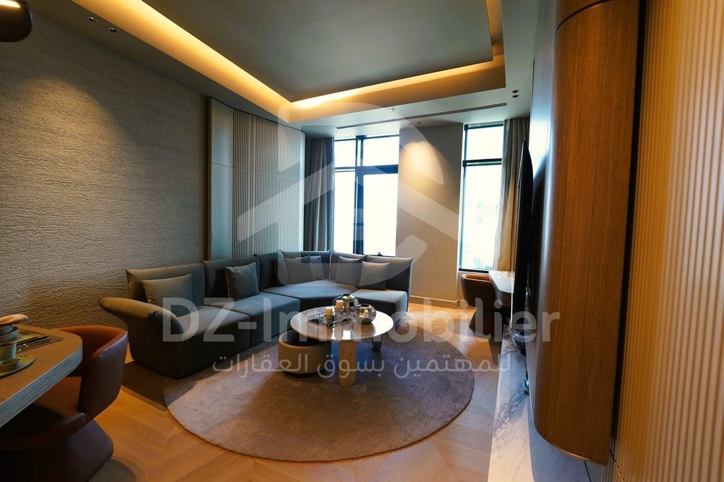 Séjour de l’appartement 1+1 meublé, canapé d’angle et fenêtres sur la ville