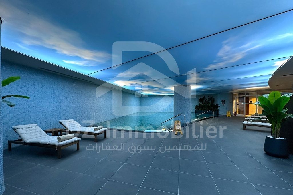 Piscine intérieure du spa avec transats et plafond décoré d’un ciel